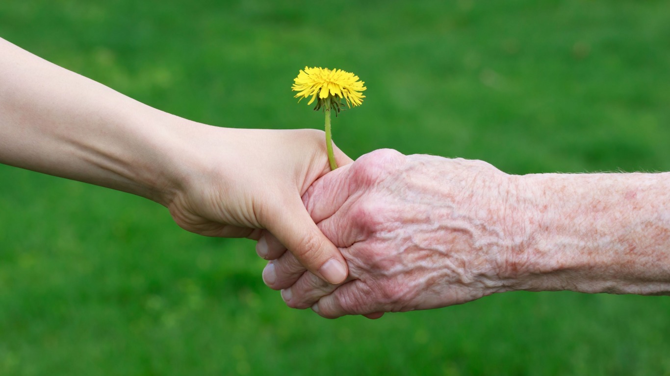 Una ragazza giovane dona un fiore ad una persona anziana affetta da demenza